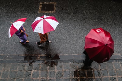 三个人打着伞在街上走